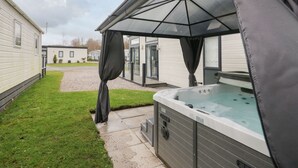 A hot tub with a canopy, a grassy area, and a pathway leading to a building. - Yealand 36 (Carnforth)