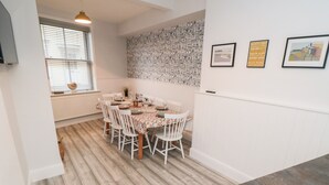 A dining area with a wooden floor, white chairs, and a table set for four.
