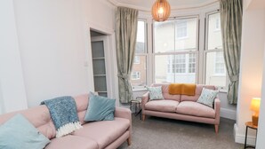 A modern living room with two sofas, a small table, and a hanging light fixture.