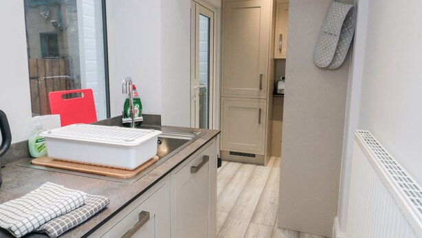 A modern kitchen with a built-in oven, a sink, and a window.