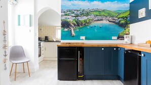 Une cuisine moderne dotée d’une grande baie vitrée offrant une vue sur une ville côtière, d’appareils électroménagers intégrés et d’un design minimaliste.
