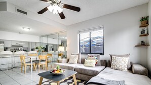 A modern living room with a sofa, a coffee table, and a dining area with chairs.