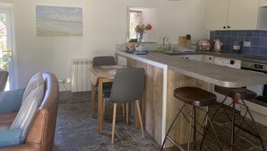 A modern kitchen with a central island, bar stools, and pendant lighting. - Downrow Barn (Tintagel)
