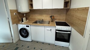 Une cuisine compacte équipée d’un lave-linge, d’une cuisinière et d’un évier.
