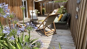 Une terrasse en bois avec un fauteuil de relaxation, une petite table et un canapé.