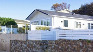 A white house with a stone wall and a wooden fence. - The Warren D7 (Pwllheli)