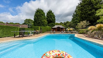 A swimming pool with lounge chairs and a small building in the background.