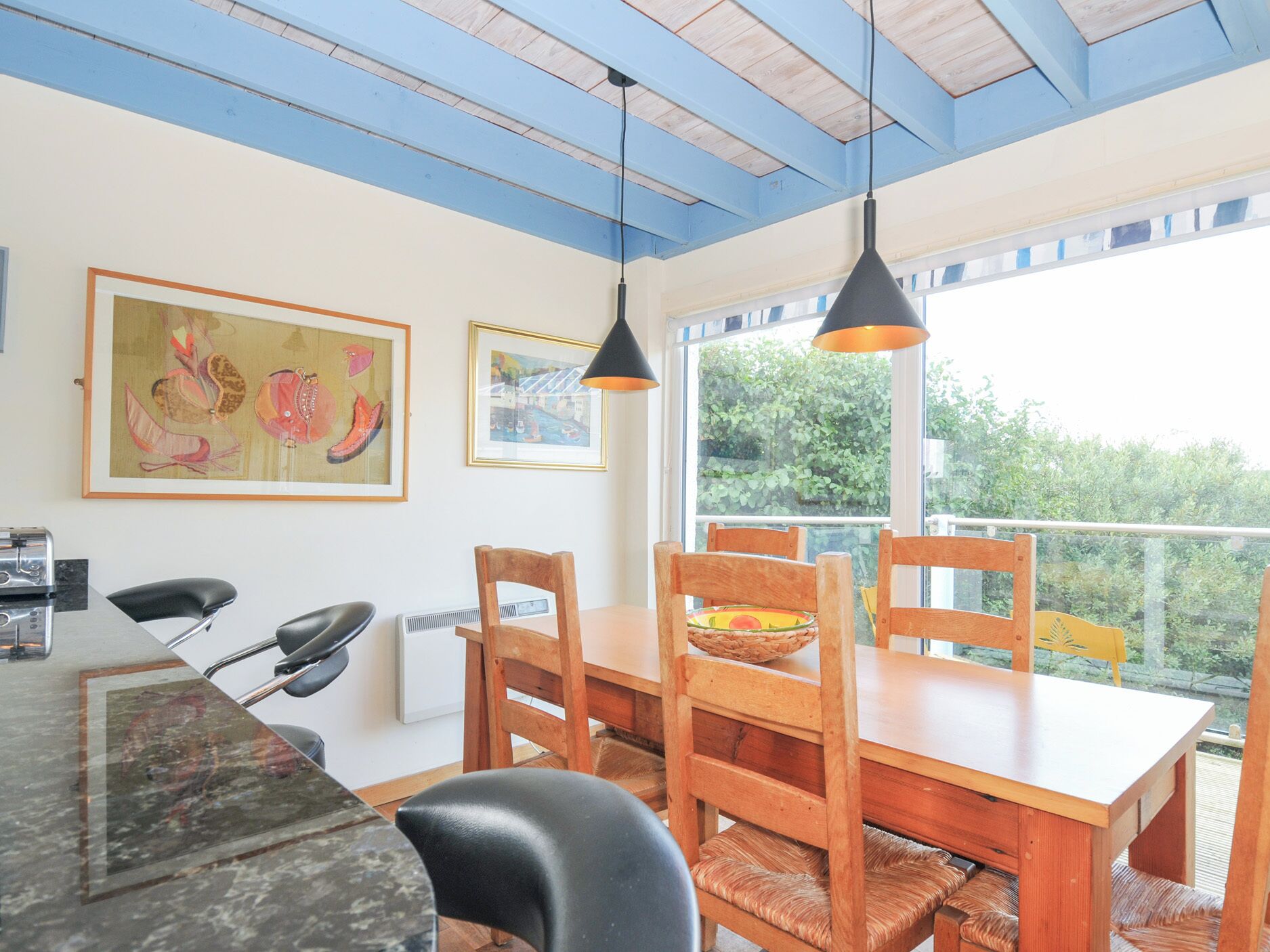 Un comedor con una mesa de madera, sillas y obras de arte en las paredes.
