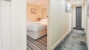 A hotel room with a bed, a nightstand, a lamp, and a painting on the wall. - Beachside (Wadebridge)