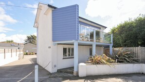 A modern two-story house with a balcony, a garage, and a fenced yard. - Beachside (Wadebridge)