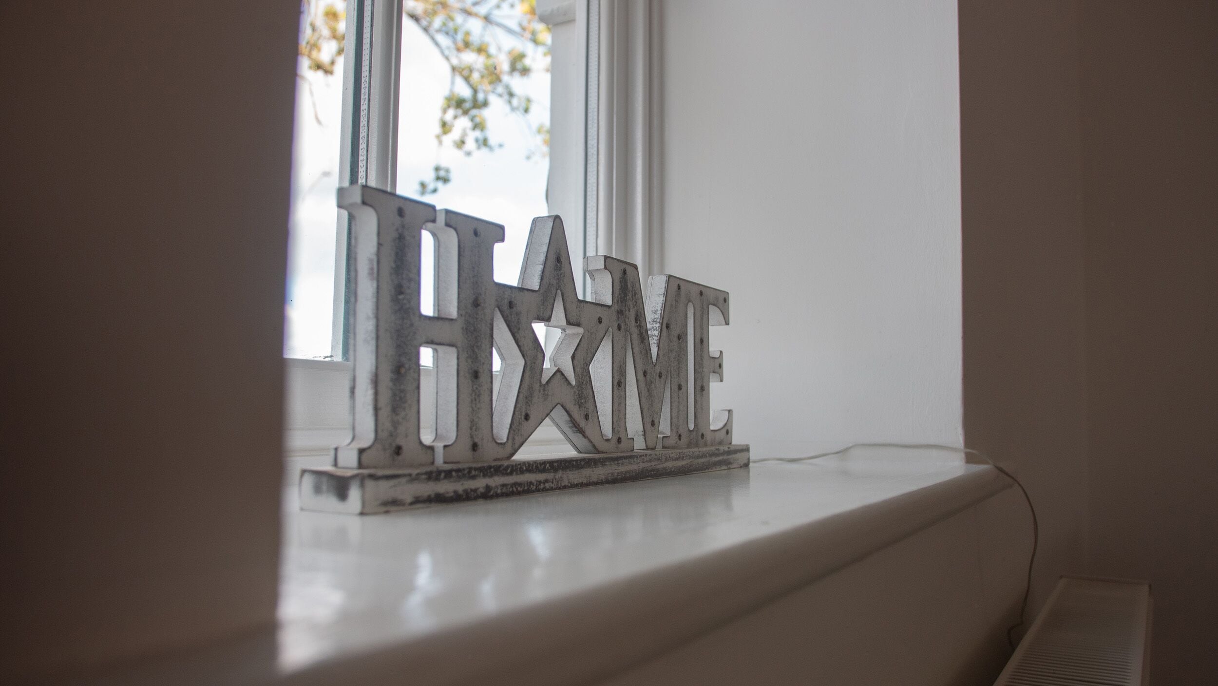 Un rebord de fenêtre orné d’une plaque métallique décorative sur laquelle on peut lire le mot « HAXME ».