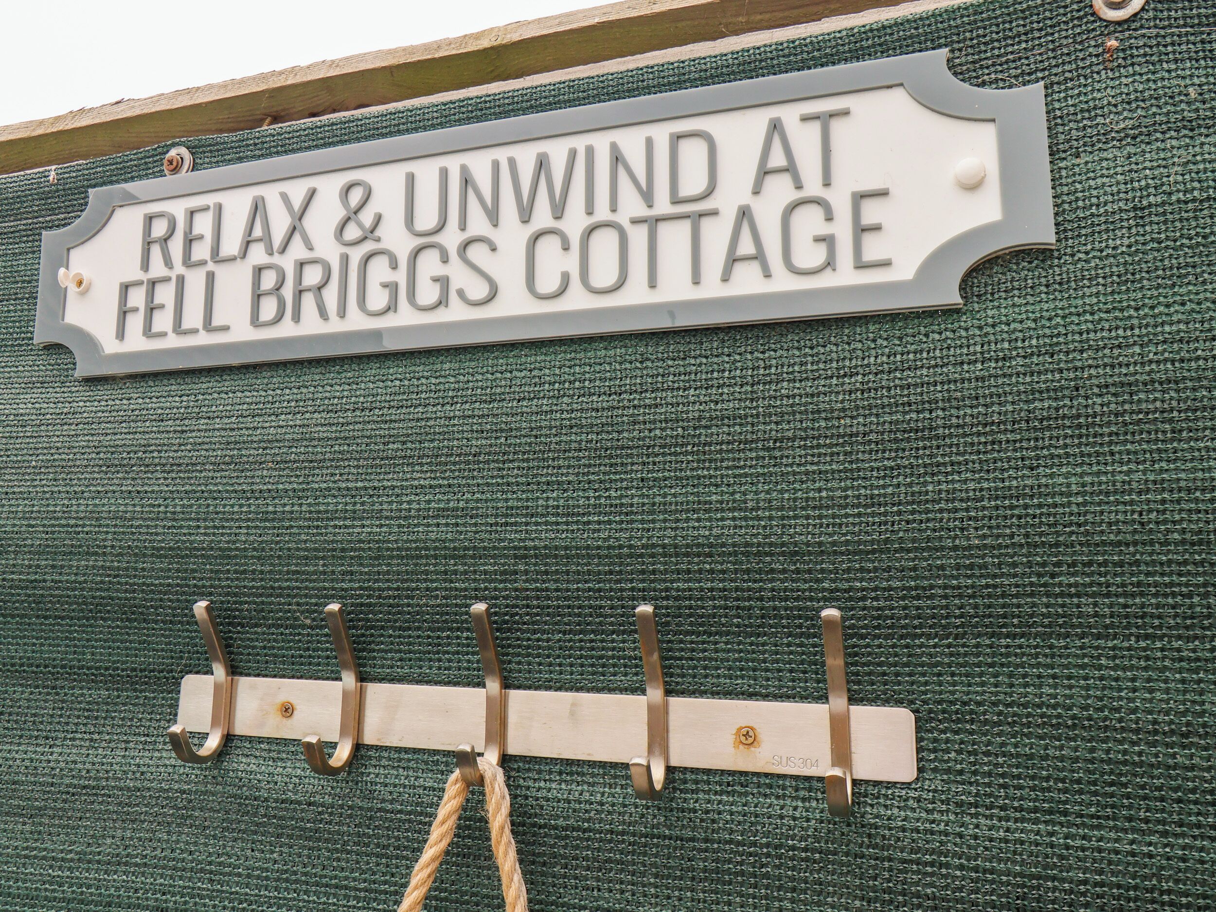 Un letrero para Fell Briggs Cottage con un perchero metálico debajo.