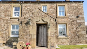 A stone building with a central entrance, two windows on each side, and a chimney. - Moss Side Retreat (Skipton)