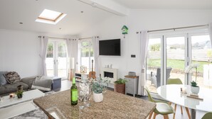 Een ruime woonkamer met keuken, eettafel en een groot raam met uitzicht op het omliggende landschap.