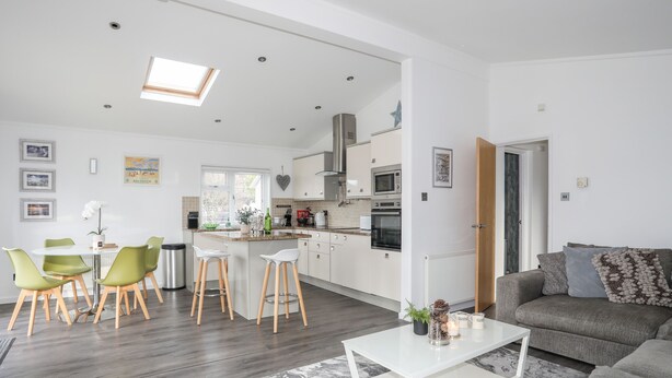 Een modern appartement met een eetgedeelte, keuken, woonkamer en een groot raam.