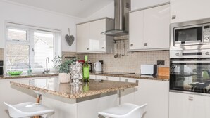 Een moderne keuken met witte kasten, granieten aanrecht en roestvrijstalen apparatuur.