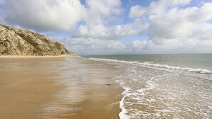 Een strand met een zandkust en golven die zachtjes op de rand spoelen.