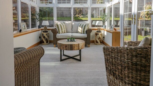 A conservatory with a glass ceiling, wicker furniture, and a central round table. - 40 Bowmont Court (Kelso)