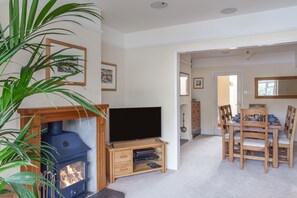 A living room with a TV, wooden entertainment unit, and a fireplace.