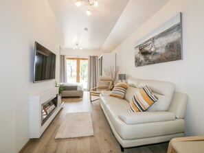 A modern living room with a sofa, a flat-screen TV, a fireplace, and a large window. - Westfields (Launceston)