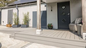 A modern building with a dark door, a covered porch, and outdoor seating. - Westfields (Launceston)
