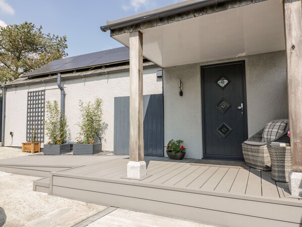 A modern building with a dark door, a covered porch, and outdoor seating. - Westfields (Launceston)
