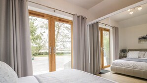 A bedroom with a large bed, a smaller bed, and a sliding glass door leading to a balcony. - Westfields (Launceston)