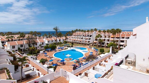 A resort with a central swimming pool, multiple balconies, and a view of the sea. - Parque Santiago II 269 - Studio with sea and pool (Playa de la Américas)