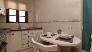 A compact kitchen with a sink, stove, and a dining area with a table and chairs. - Parque Santiago II 269 - Studio with sea and pool (Playa de la Américas)
