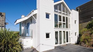 Une maison moderne à deux étages, dotée d’une grande baie vitrée et d’un vaste porche à l’avant.