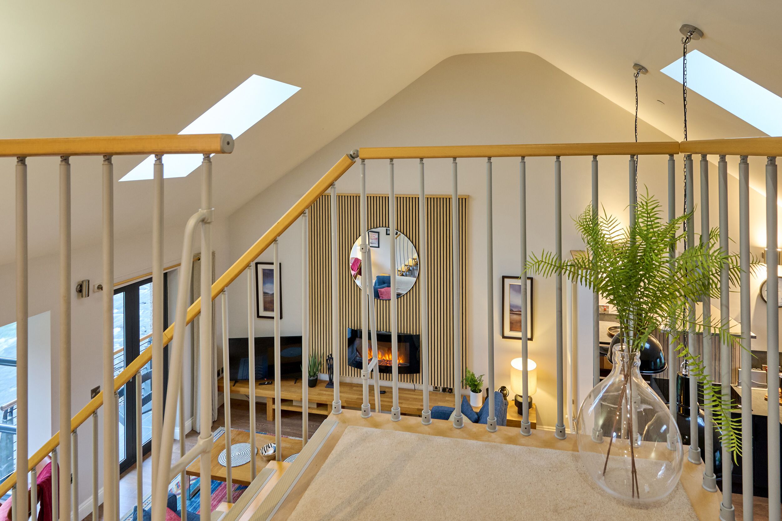 Un intérieur moderne avec un escalier, une cheminée et une grande fenêtre.