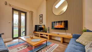 A modern living room with a fireplace, a large mirror, and a sofa. - Riverside Park 5 (Keswick)