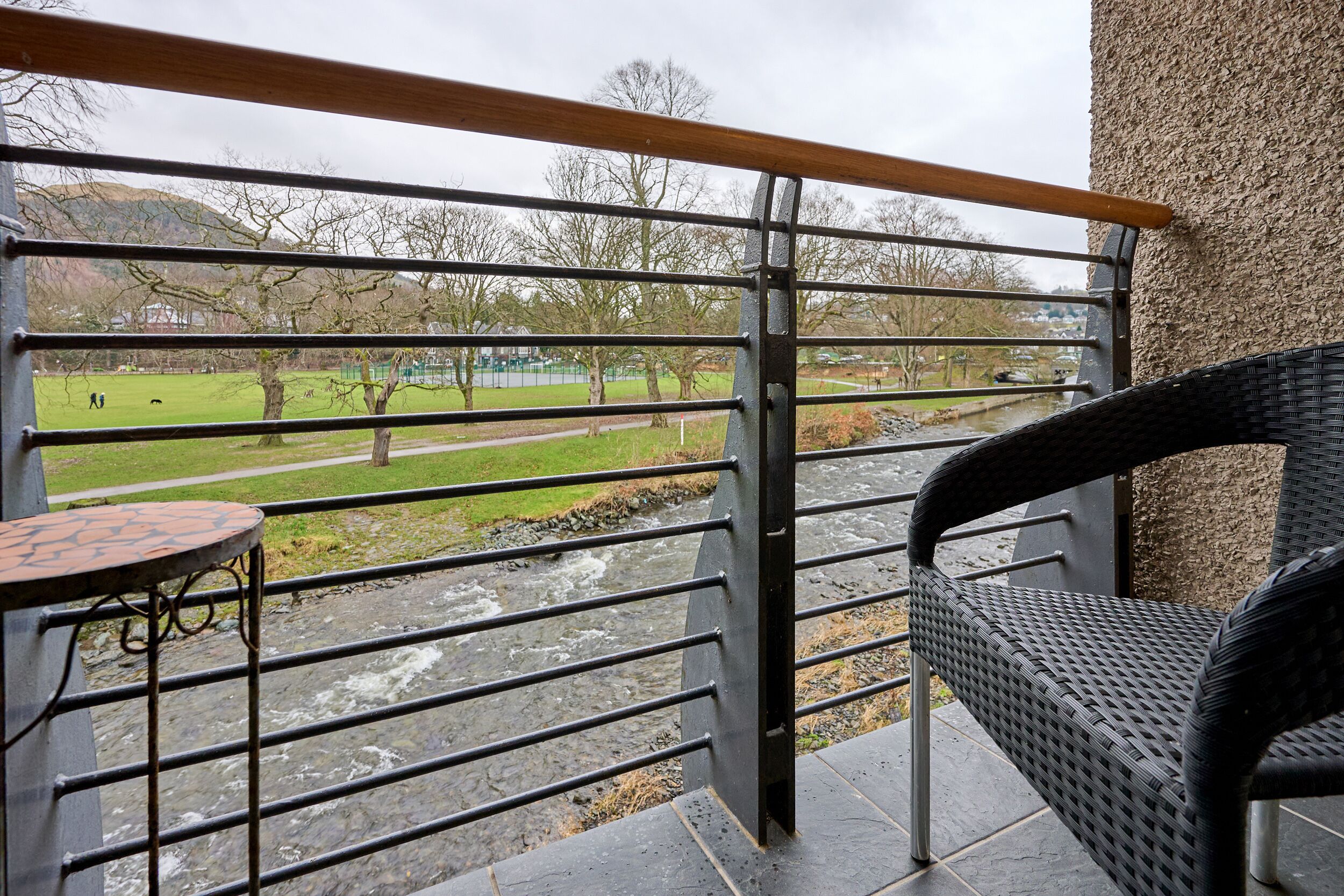 A balcony with a view of a park and a river.