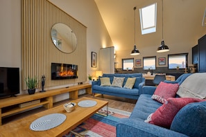 A modern living room with a fireplace, blue sofa, wooden coffee table, and a large mirror.