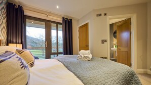 A hotel room with a large bed, a view of the outdoors, and a wooden door. - Riverside Park 5 (Keswick)