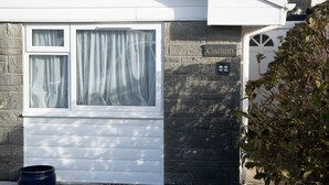 Een huis met huisnummer 22, een raam met gordijnen en een bakstenen muur.