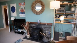 Een woonkamer met een open haard, een televisie, een boekenkast en een eethoek.