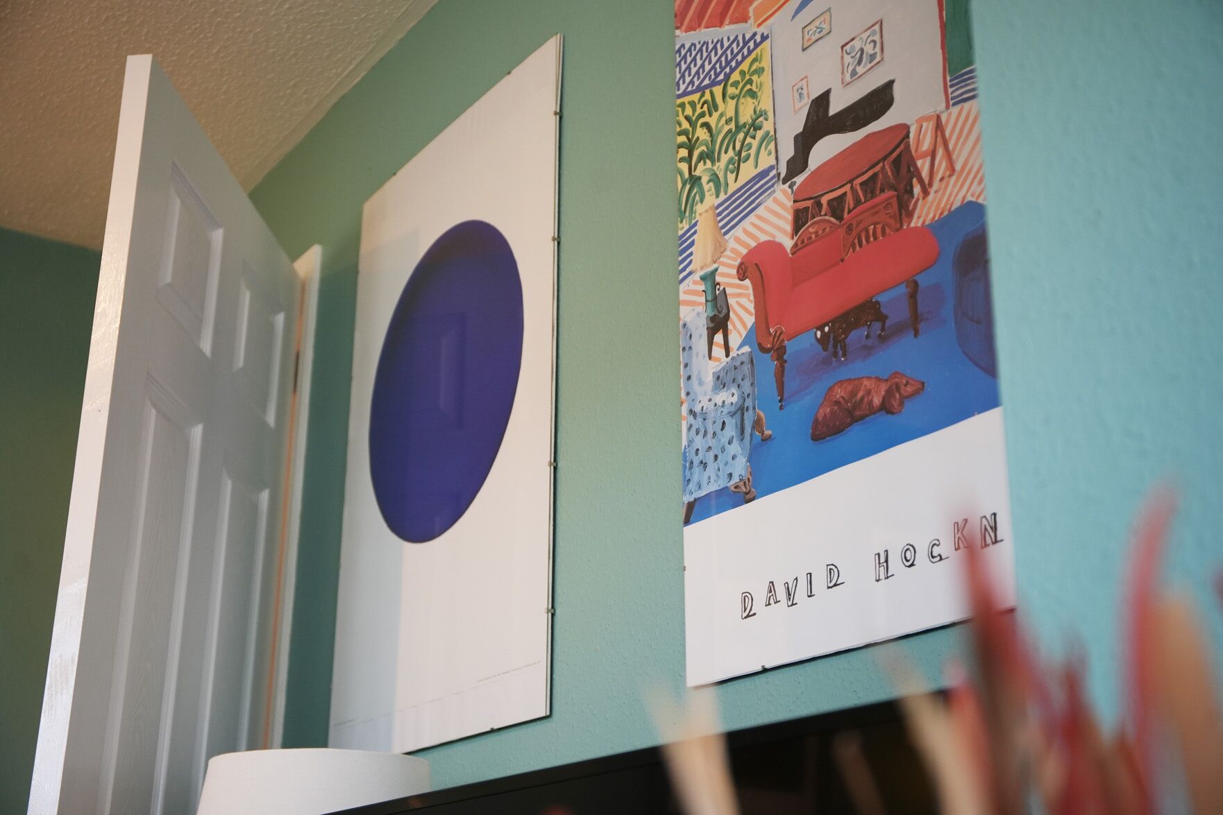 A room with a door, a framed artwork, and a wall with a colorful illustration.