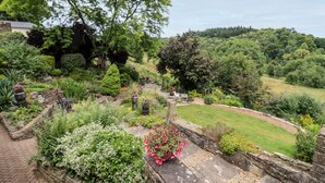 A garden with a stone pathway, various plants, and a bench. - The Stable (Lydney)
