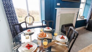 A dining area with a round glass table set for four, surrounded by chairs. - The Stable (Lydney)
