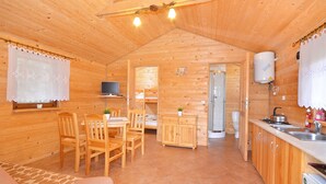 A wooden cabin interior with a dining area, kitchen, and bathroom. - Serene Bungalow in Darłowo with Large Garden (Darłowo)
