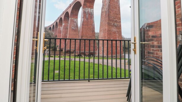 Blick auf einen Ziegelviadukt durch eine Glastür mit einem Metallgeländer.