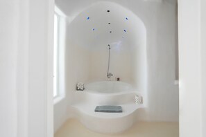 A modern bathroom with a freestanding bathtub, a small sink, and a window providing natural light. - Villa Super One (Kalamata)