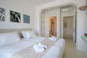 Habitación de hotel con dos camas, ropa de cama blanca, un ventanal grande y obras de arte en la pared.