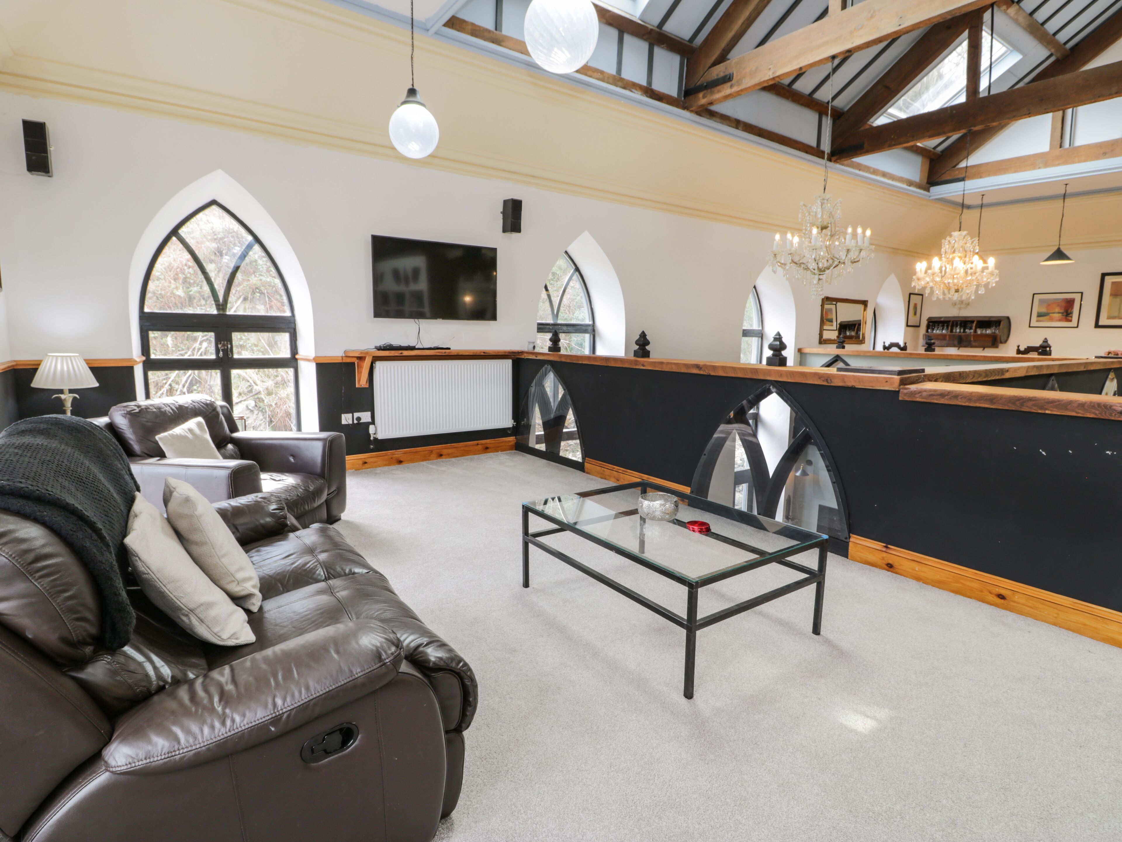 A spacious living room with a leather sofa, a glass coffee table, and a black accent wall.