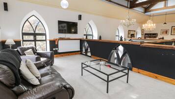 A spacious living room with a leather sofa, a glass coffee table, and a black accent wall.