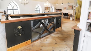 A spacious kitchen with a wooden island, large windows, and a chandelier. - Greystones Chapel (Caernarfon)