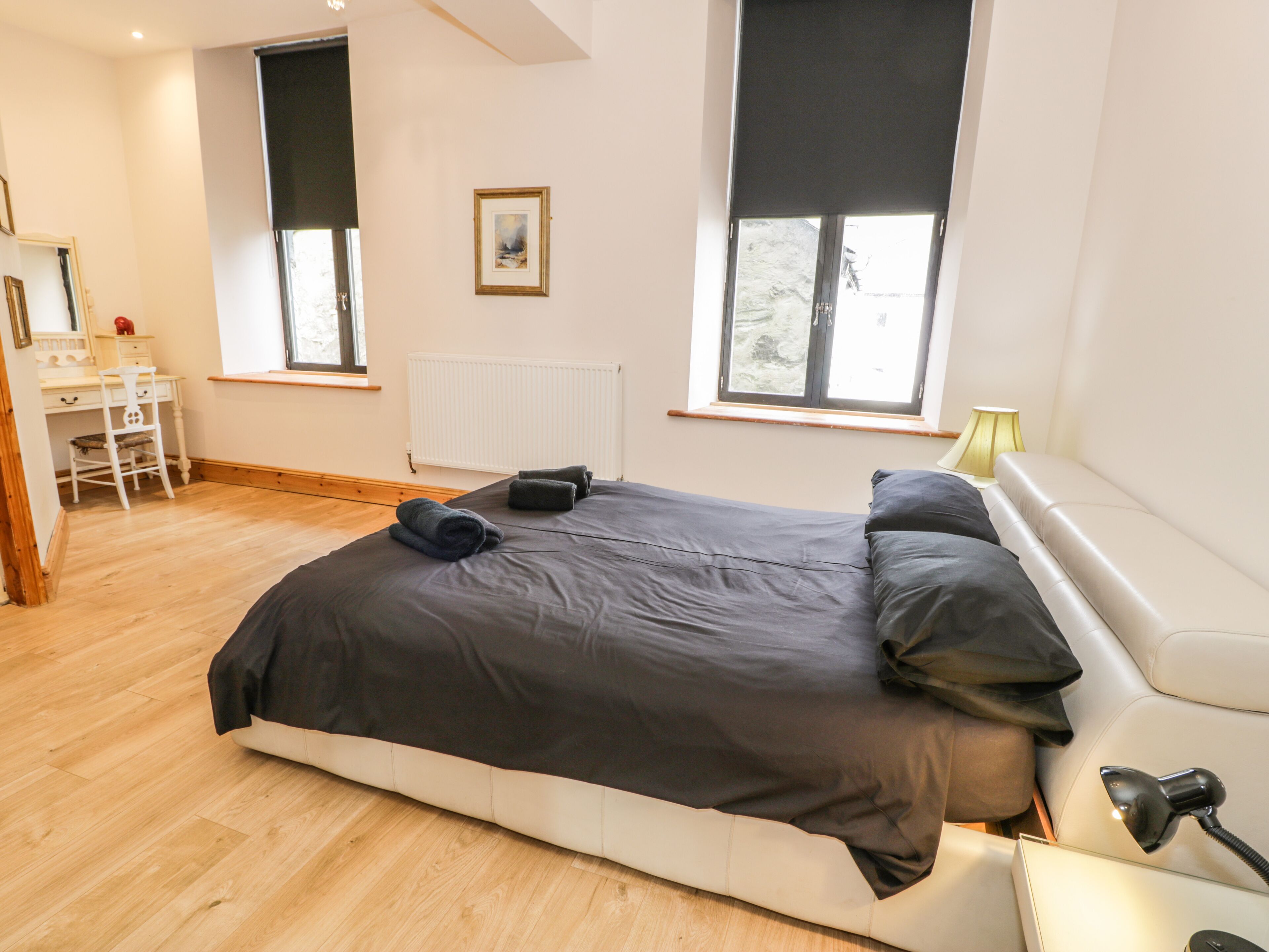 A bedroom with a large bed, a desk, and a chair.