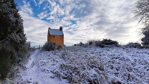 Paesaggio innevato con una struttura a torre solitaria sullo sfondo.
