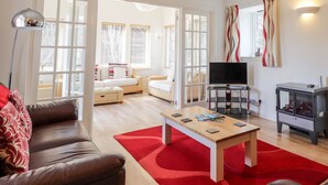 Un soggiorno moderno con un divano in pelle, un tavolino in legno e una televisione. Sul pavimento è presente un tappeto rosso, e sullo sfondo si nota un camino.